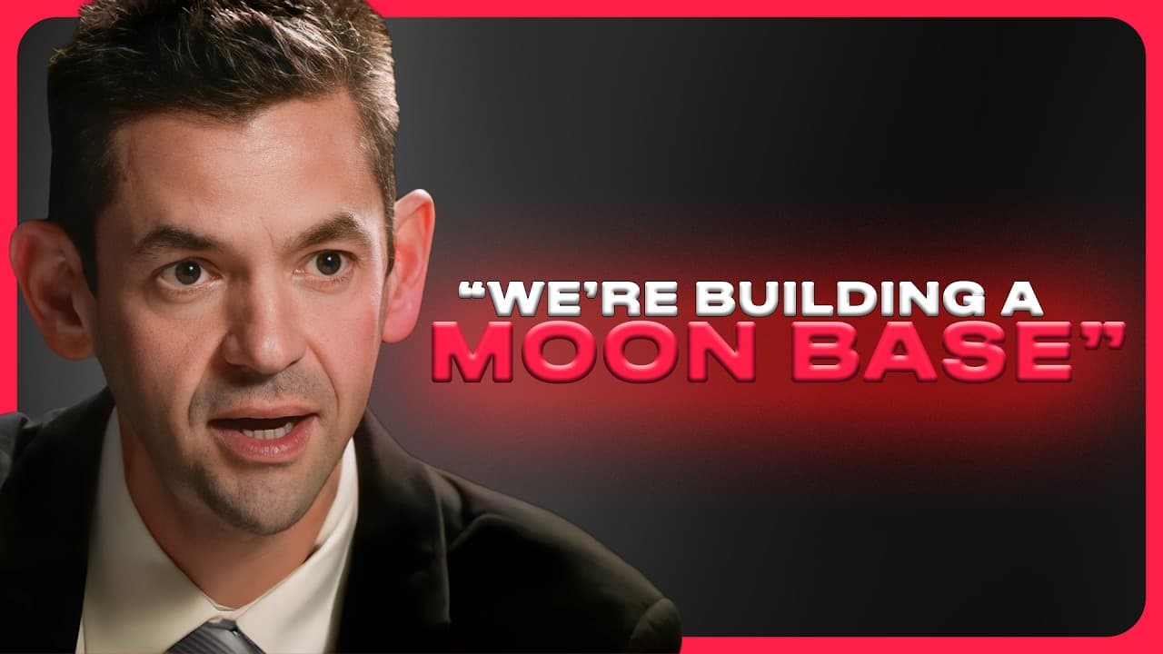 Two men in suits sitting at a table with microphones, discussing space exploration.