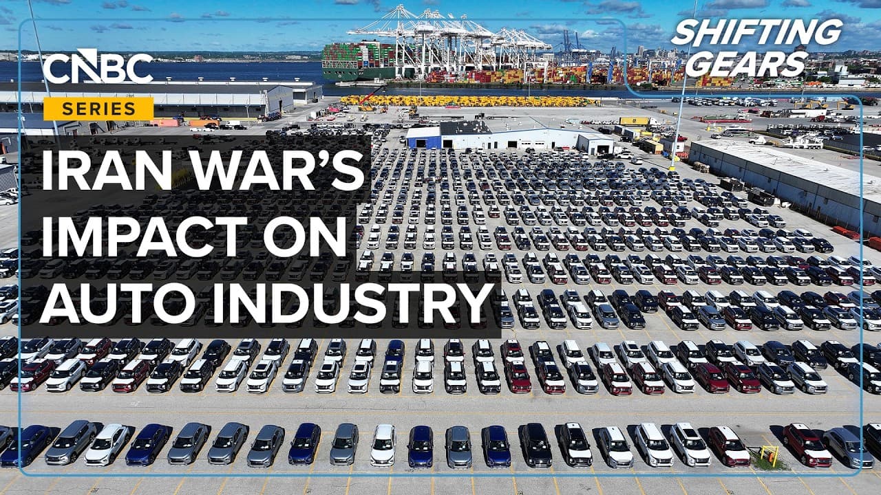 Aerial view of a busy automotive factory assembly line with robots working on car frames.