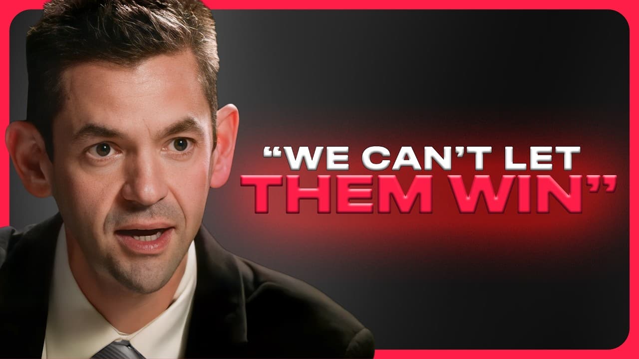 Joe Lonsdale speaking into a microphone with an American flag in the background.