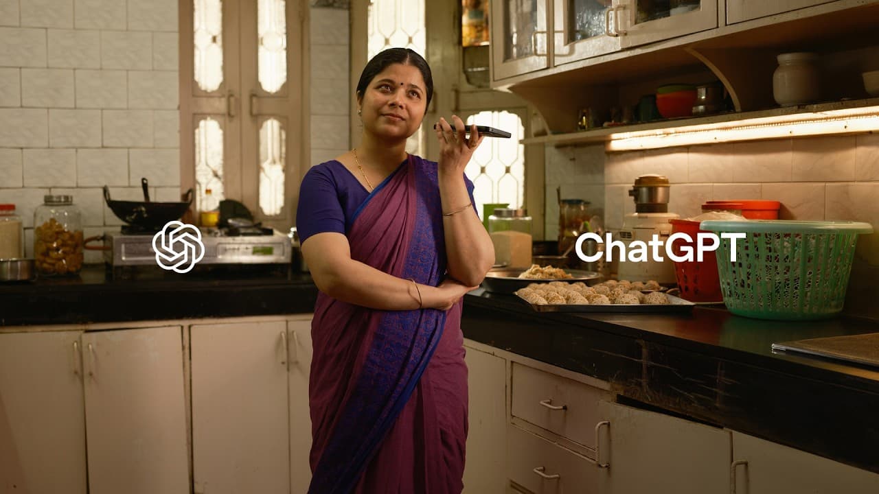 A woman in a sari wearing gloves, preparing small round sweets coated in sesame seeds on a tray.