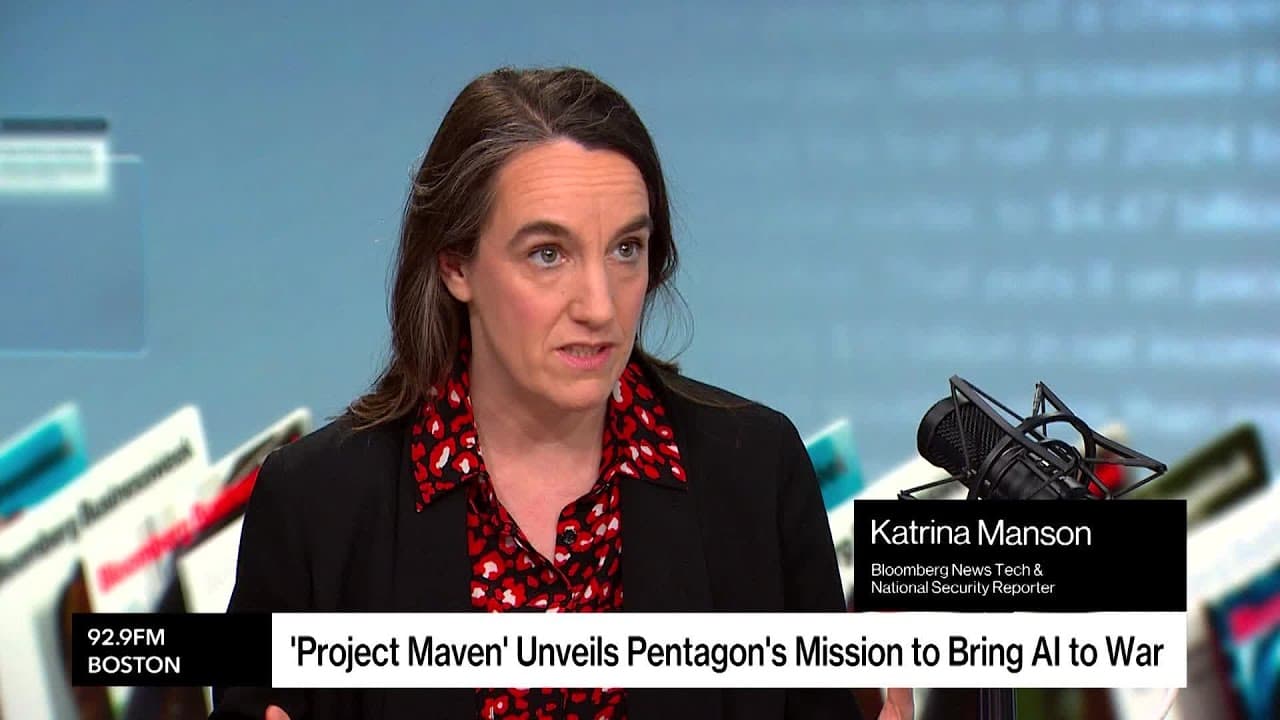 Three people sitting at a circular desk in a studio, discussing Project Maven.